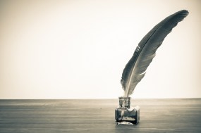 Vintage background with quill pen and inkwell on table